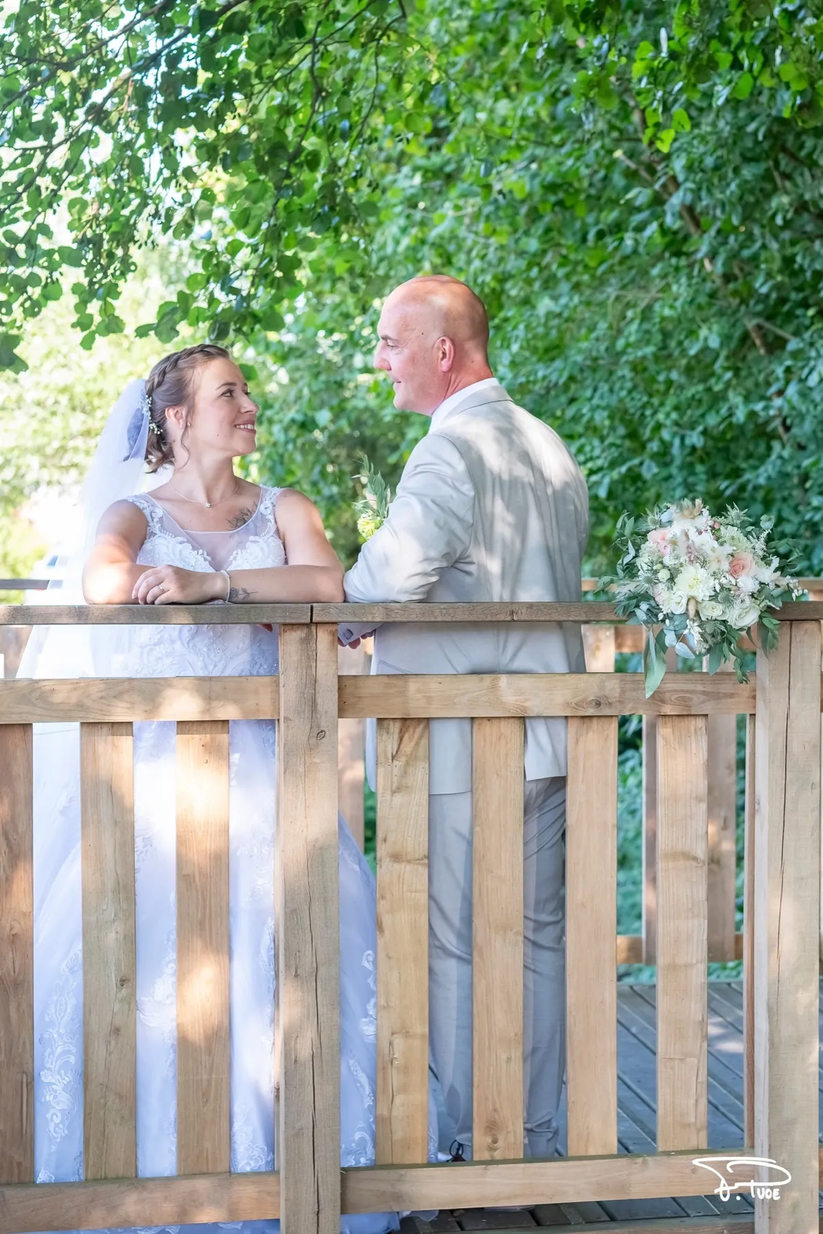 Les mariés accoudés à la barrière d’un ponton en bois