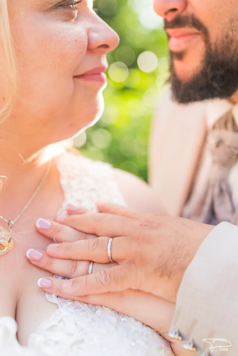 La main du marié, alliance au doigt, posée sur le cœur de la mariée