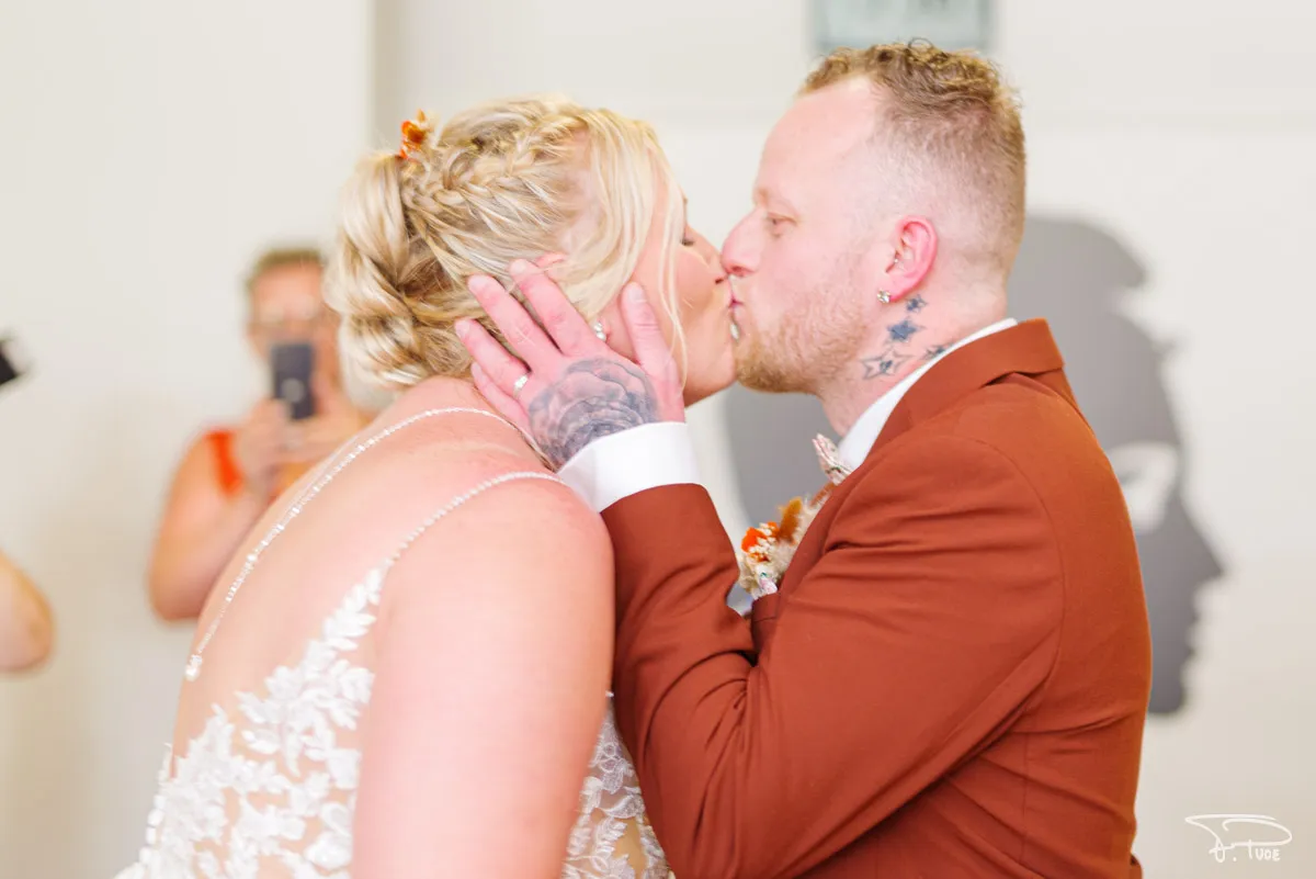 Les mariés s’embrassent, la main tatouée du marié sur la joue de la mariée