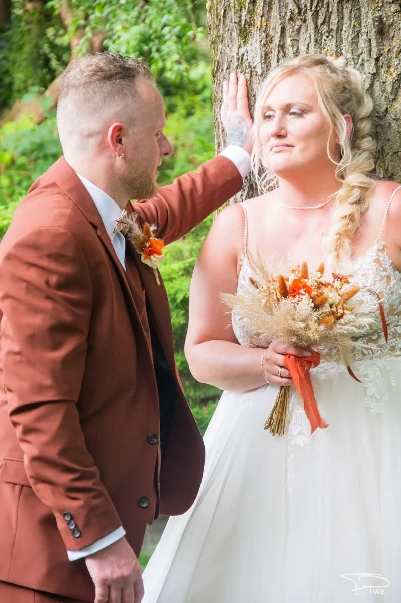 Le marié glisse la main dans les cheveux tressés de la mariée