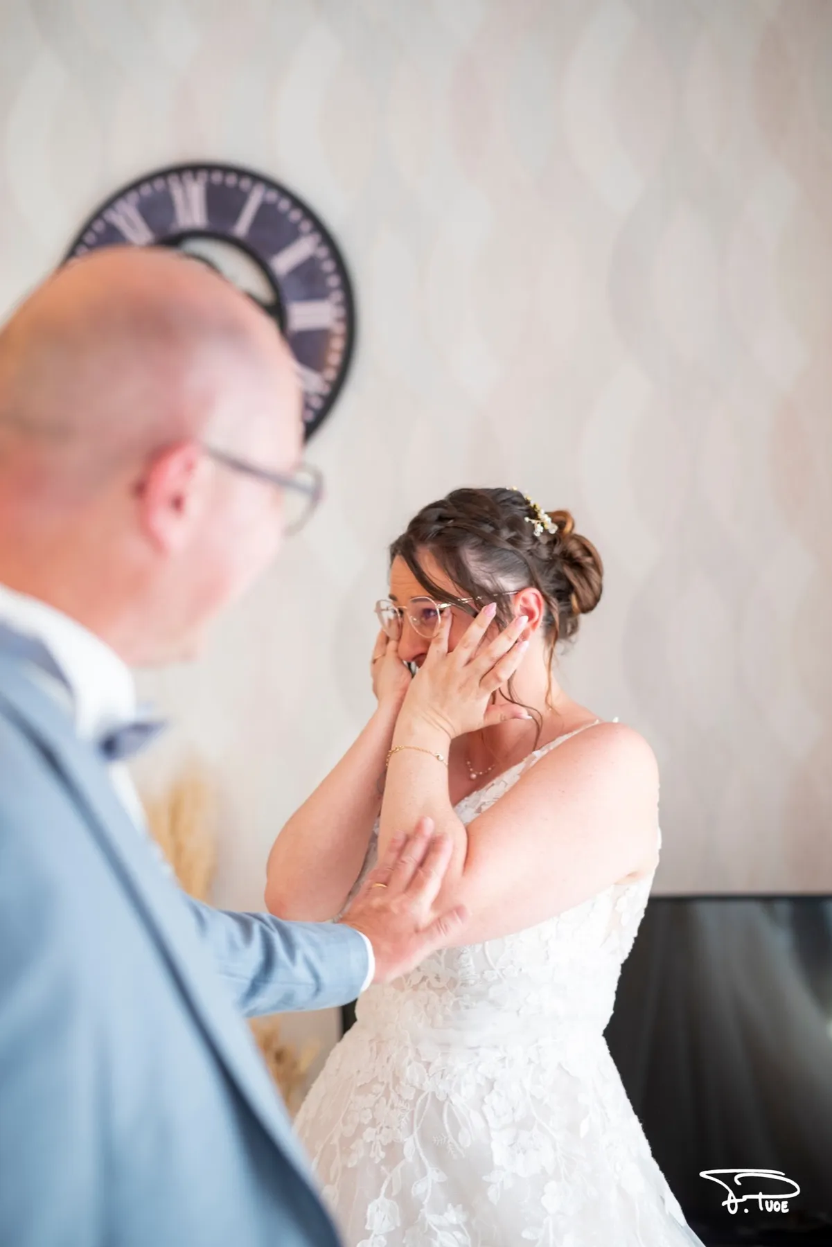 La mariée, émue, porte les mains à son visage en découvrant le marié