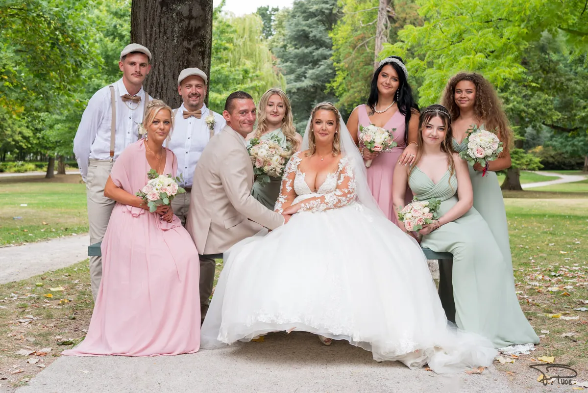 Les mariés entourés de leurs témoins et demoiselles d’honneur en robes pastel, dans un parc