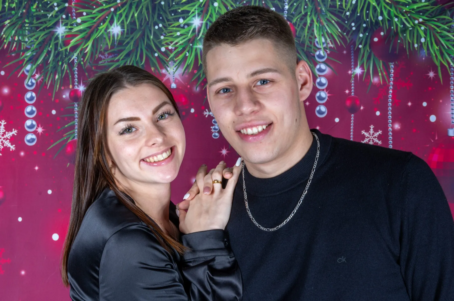 Jeune couple souriant devant un décor de Noël en studio