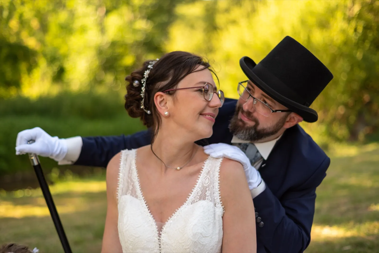 La mariée rit en regardant le marié en haut-de-forme, penché sur elle, dans une lumière dorée