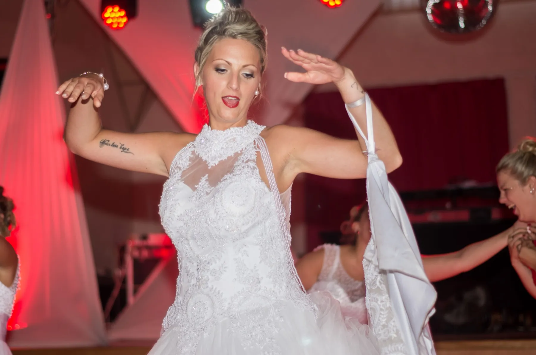 La mariée danse sous les lumières rouges de la soirée