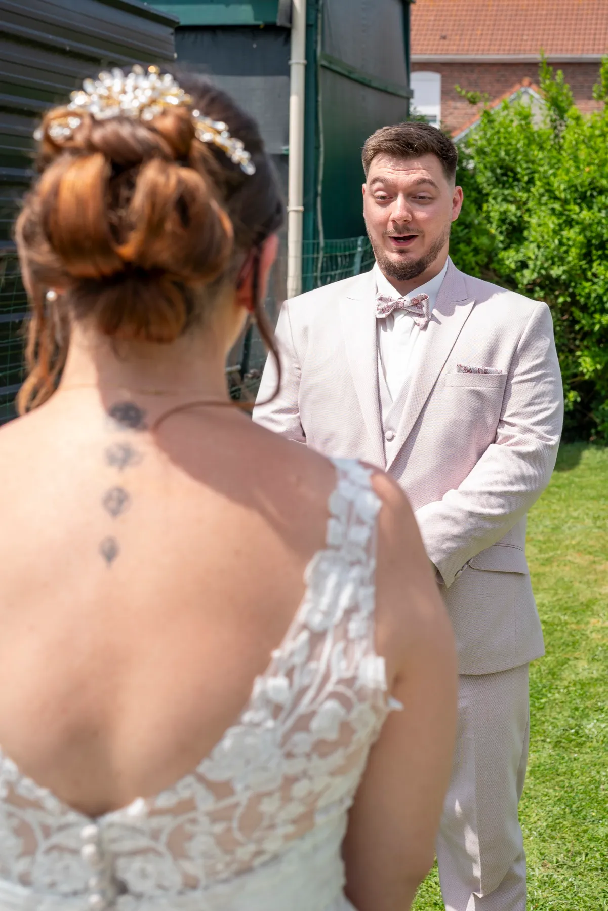 Le marié découvre la mariée, vue de dos avec ses fleurs dans les cheveux