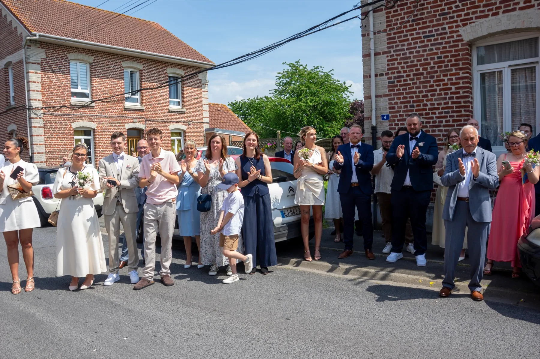 Dans la rue, devant les maisons en briques, les invités applaudissent