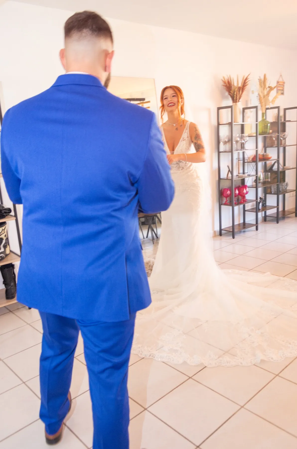 Vu de dos, le marié s’avance vers la mariée qui lui sourit