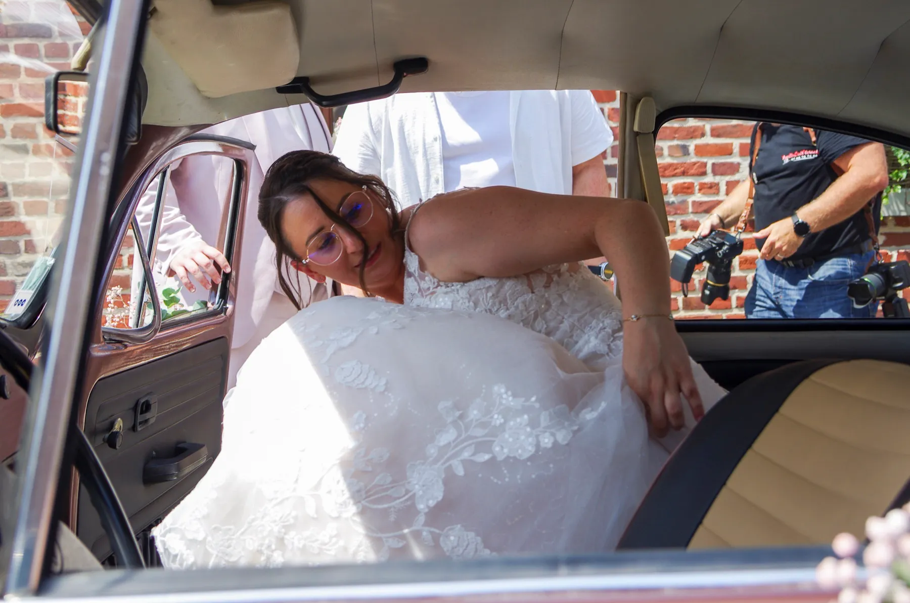La mariée se glisse sur la banquette de la Coccinelle, sa robe de dentelle autour d’elle