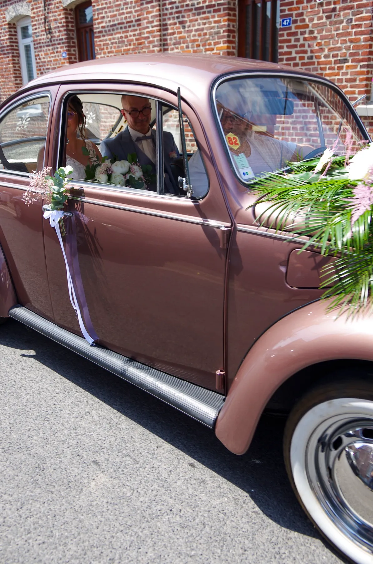 À travers la vitre de la Coccinelle, la mariée assise à côté de son papa, en route pour la mairie