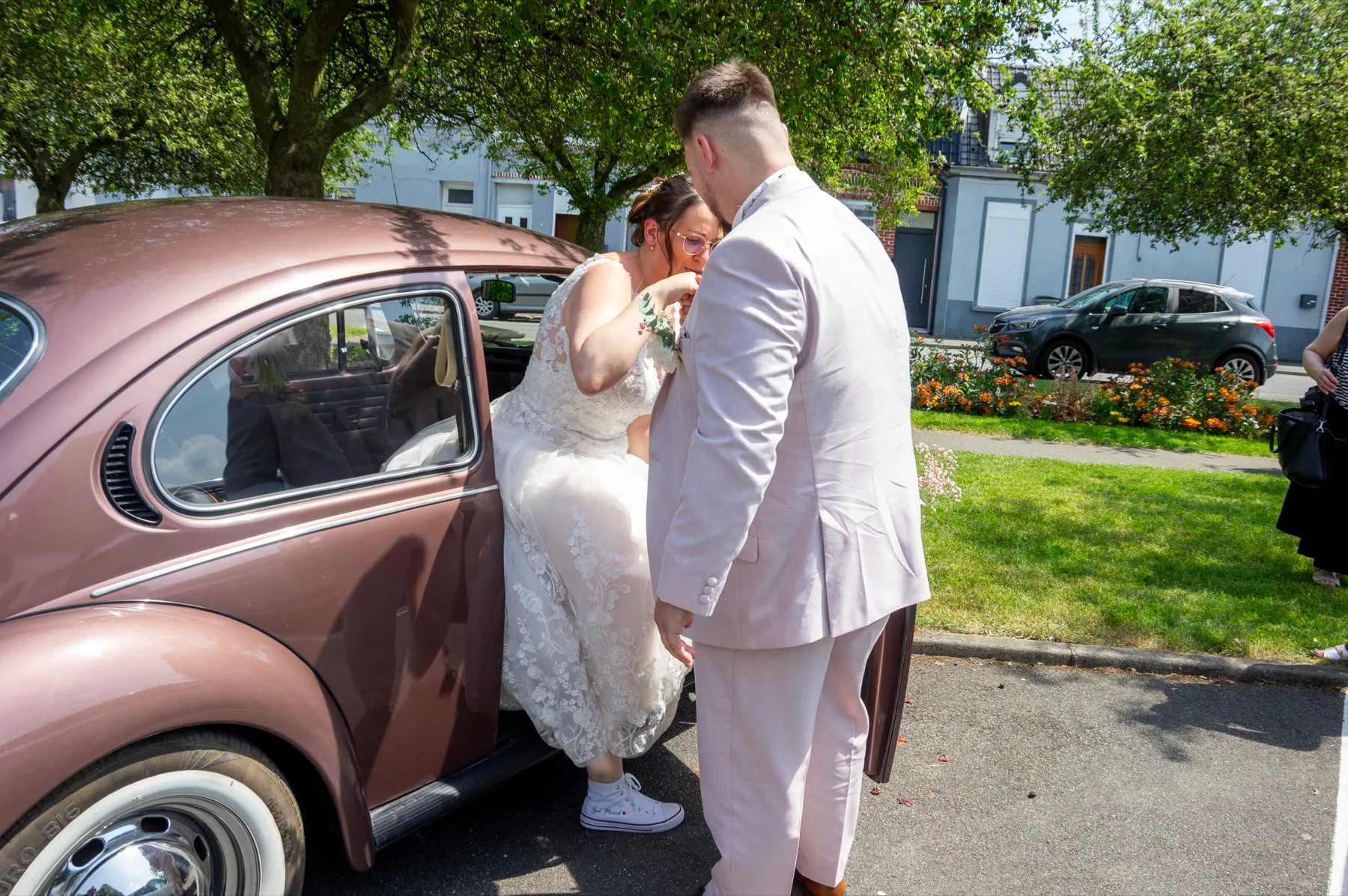 Le marié aide la mariée à sortir de la Coccinelle vieux rose