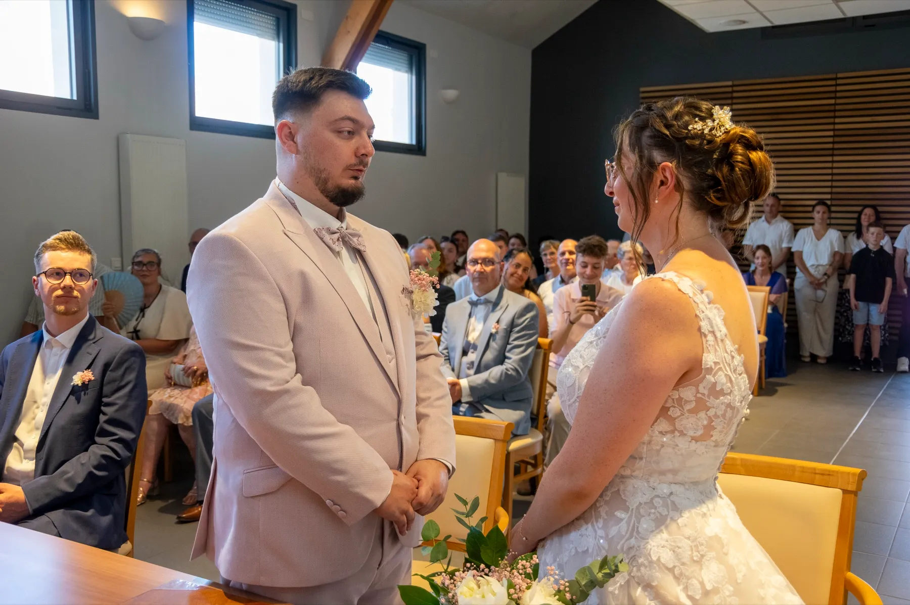 Les mariés debout face à face, devant les invités assis