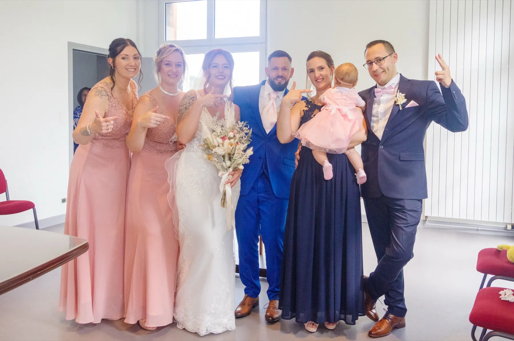 Les mariés posent à la mairie avec quatre proches et un bébé en robe rose