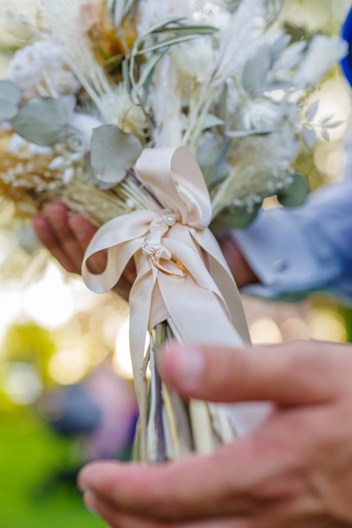 Gros plan sur le bouquet de fleurs séchées, les alliances nouées à son ruban