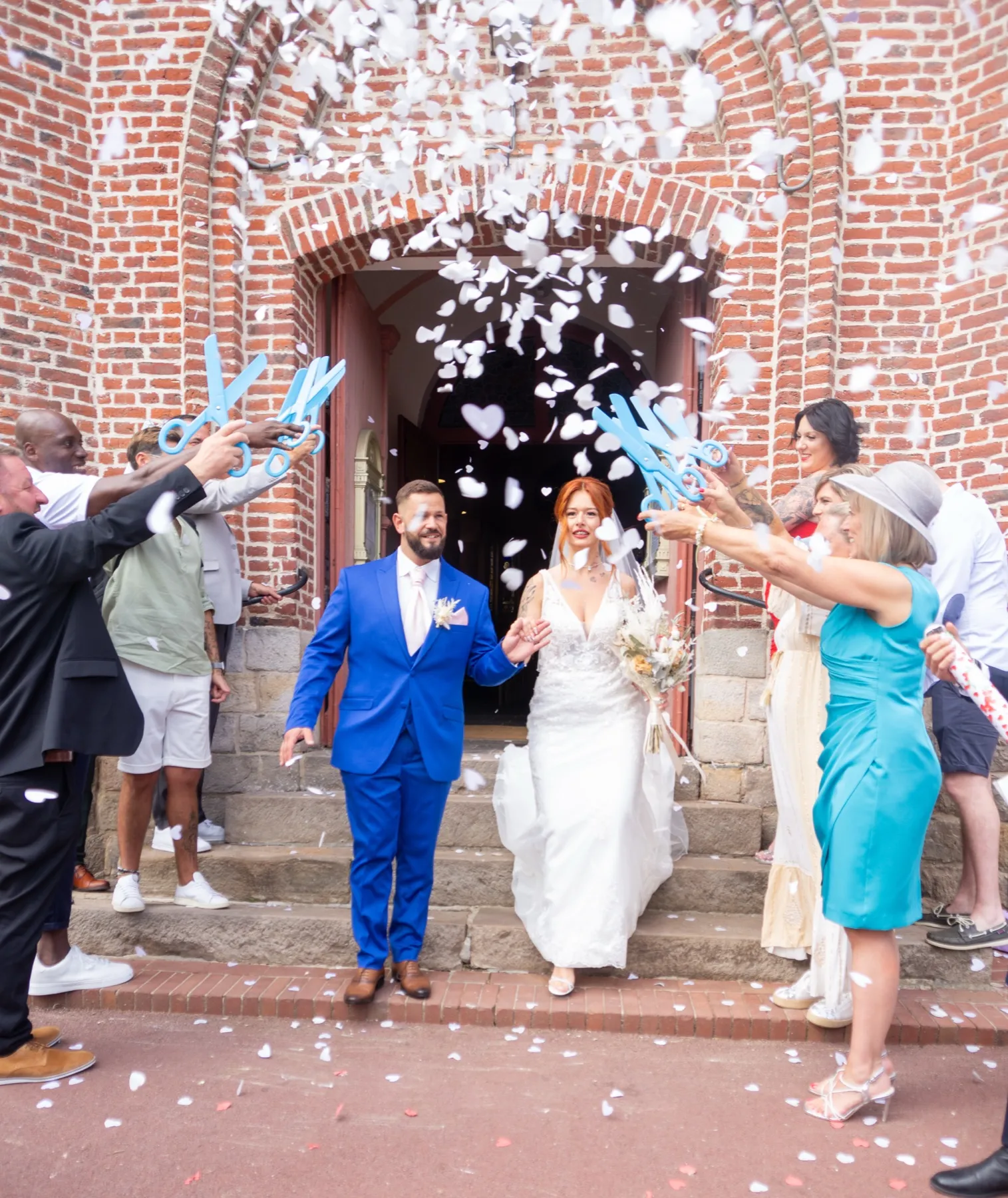 Les mariés sortent de l’église sous une pluie de confettis blancs