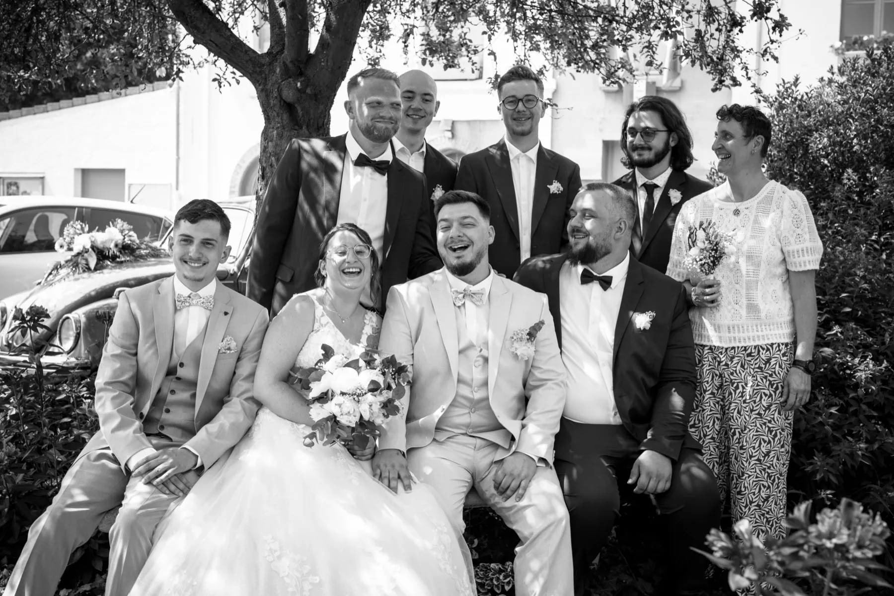 En noir et blanc, les mariés assis sur un banc, entourés de cinq proches