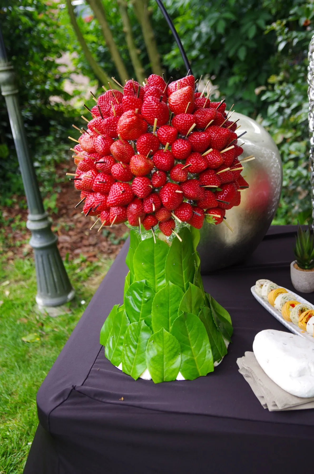 Une pyramide de fraises piquées sur un socle de feuilles, posée sur le buffet