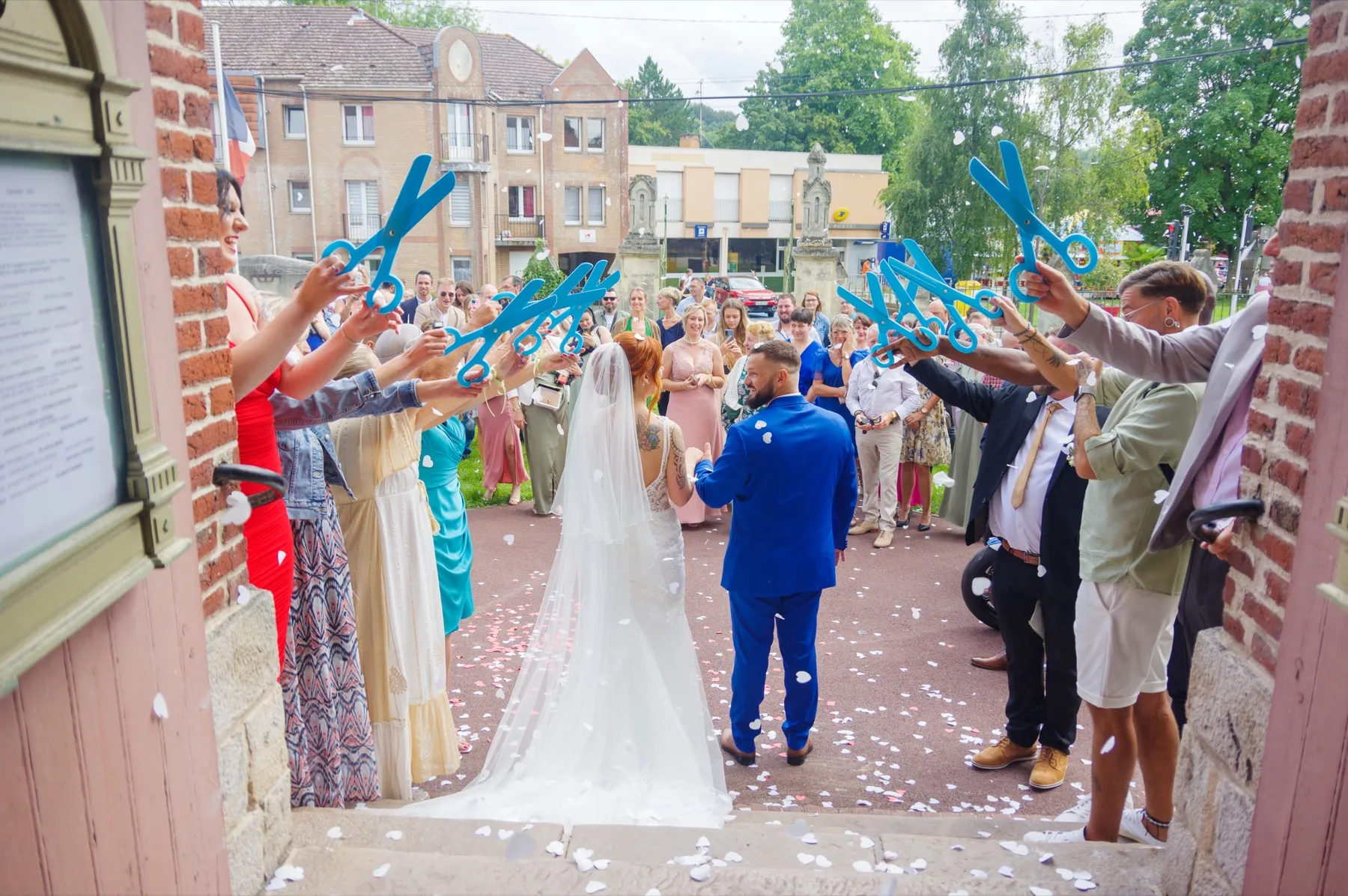 Vus de dos, les mariés font face à leurs invités rassemblés devant l’église