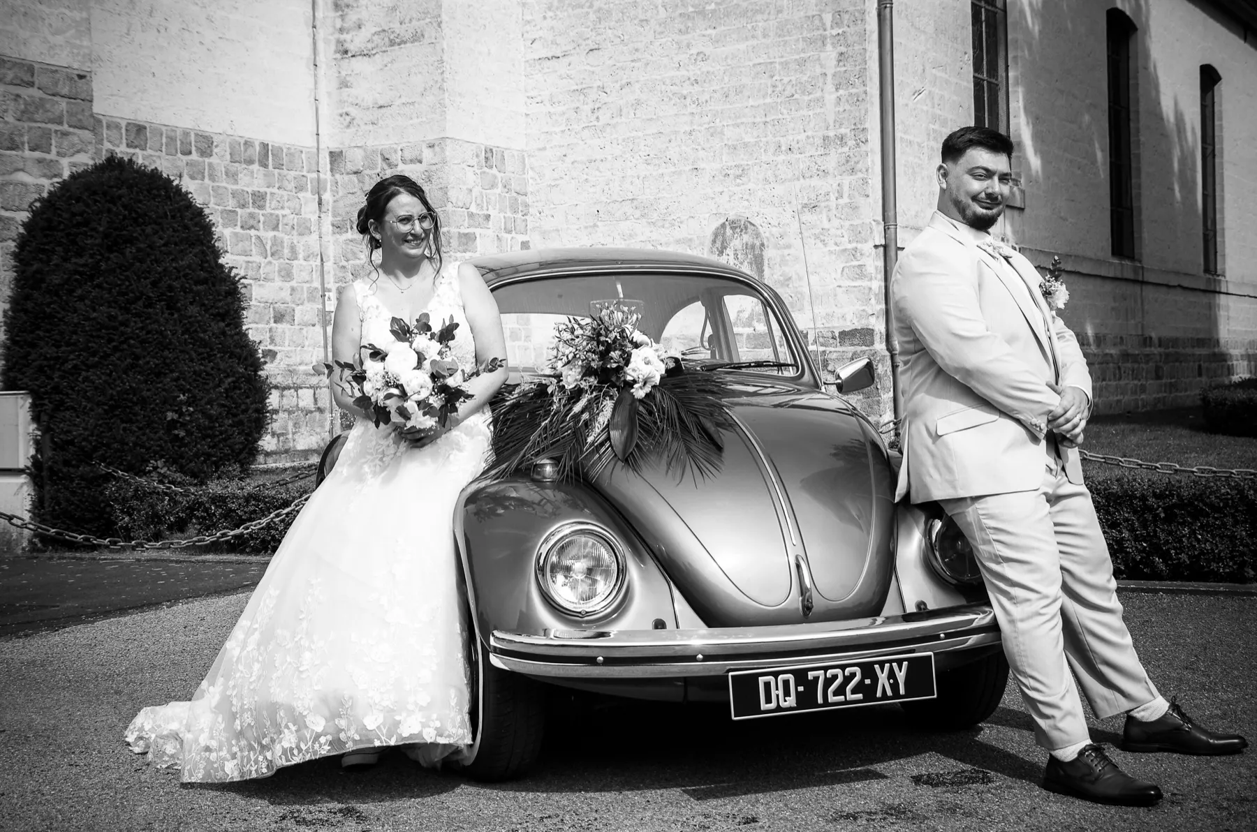 En noir et blanc, les mariés de part et d’autre de la Coccinelle fleurie