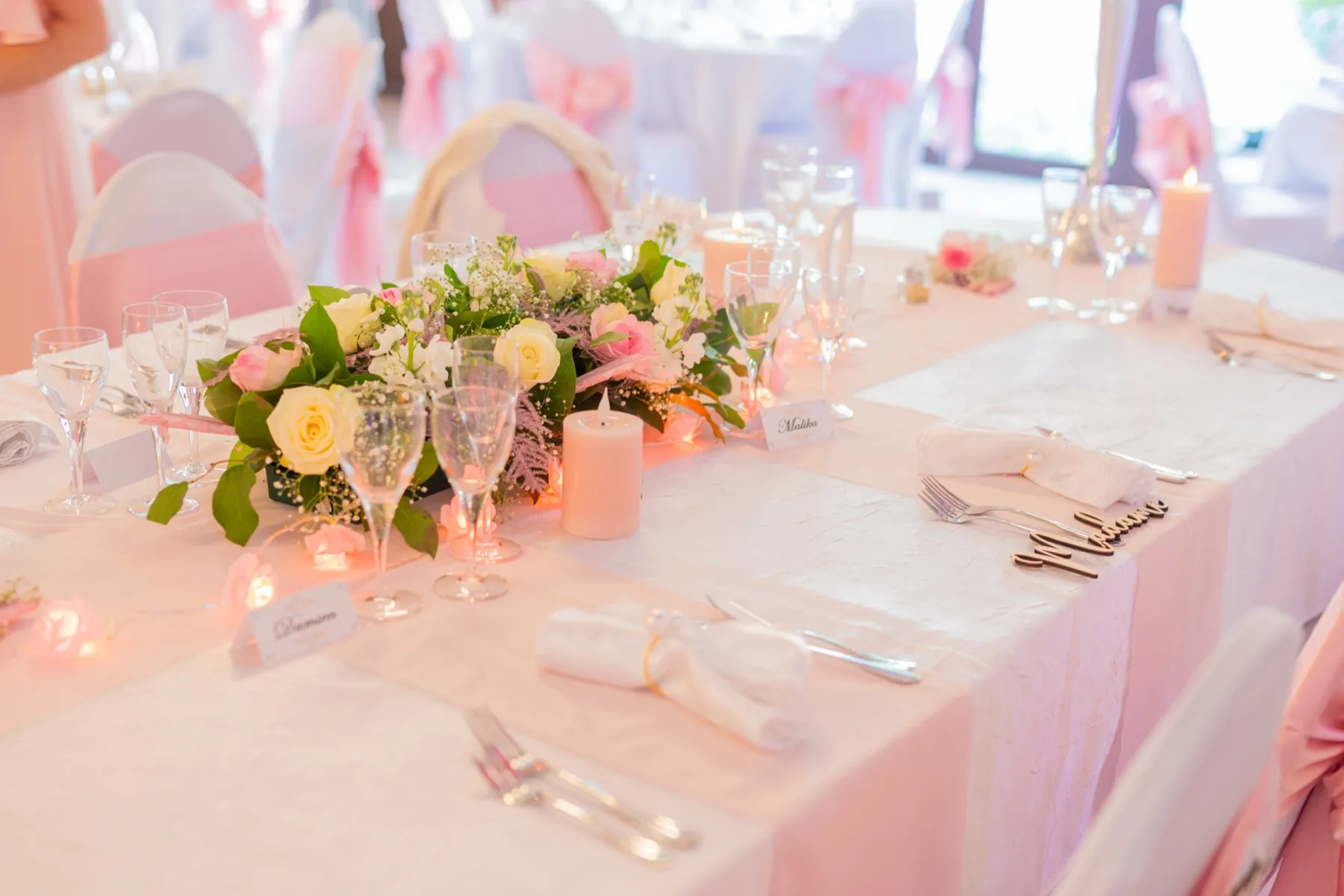 Un centre de table de roses blanches et roses, entouré de bougies et de verres