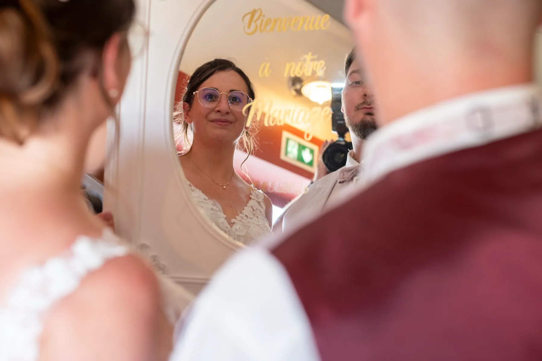 La mariée se reflète dans un miroir où est écrit « Bienvenue à notre mariage »