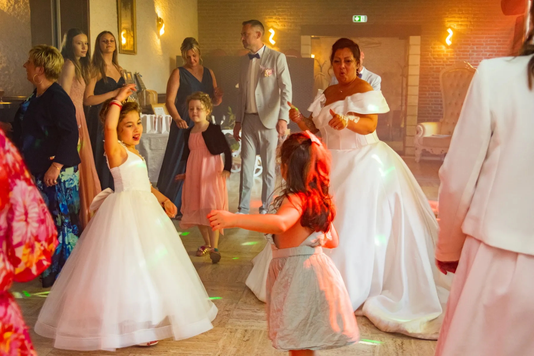 Sur la piste, la mariée danse avec des invités et deux petites filles
