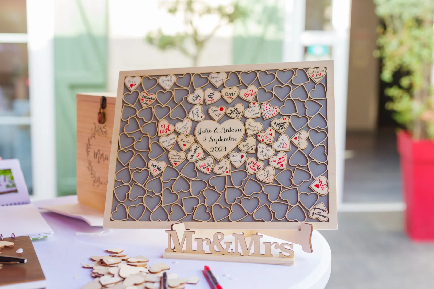 Un cadre de cœurs en bois signés par les invités, gravé « Julie & Antoine, 2 septembre 2023 »
