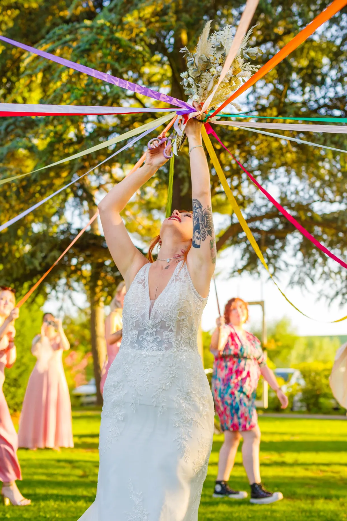La mariée lève son bouquet, d’où partent des rubans de toutes les couleurs