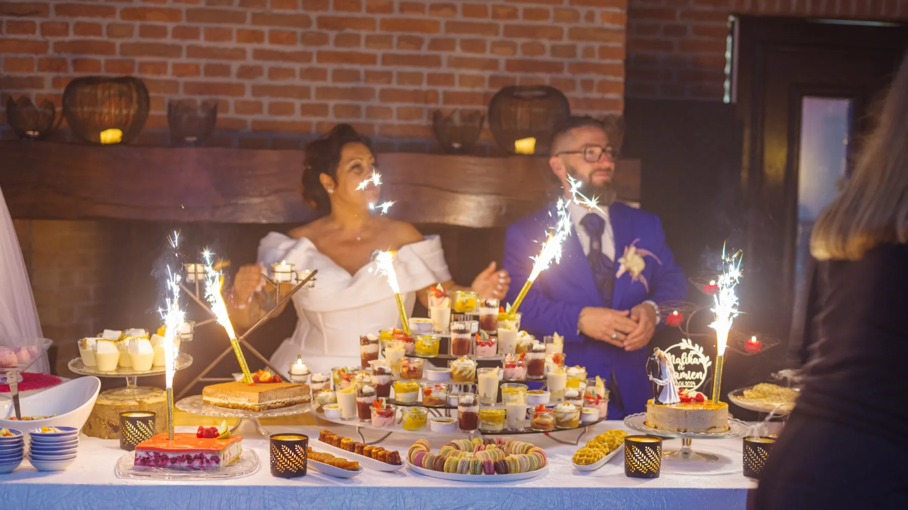 Les mariés derrière le buffet de desserts, entre des fontaines d’étincelles