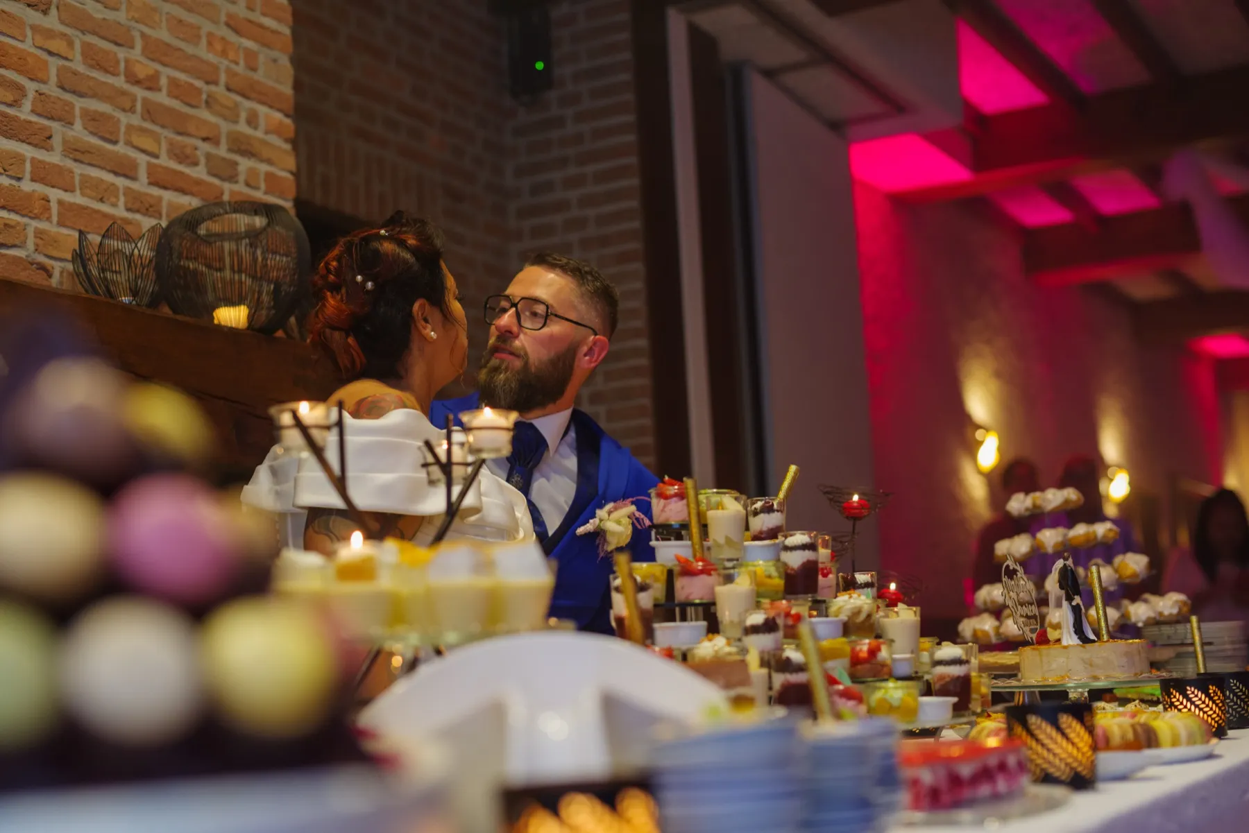 Les mariés se regardent derrière le buffet de desserts, des macarons flous au premier plan