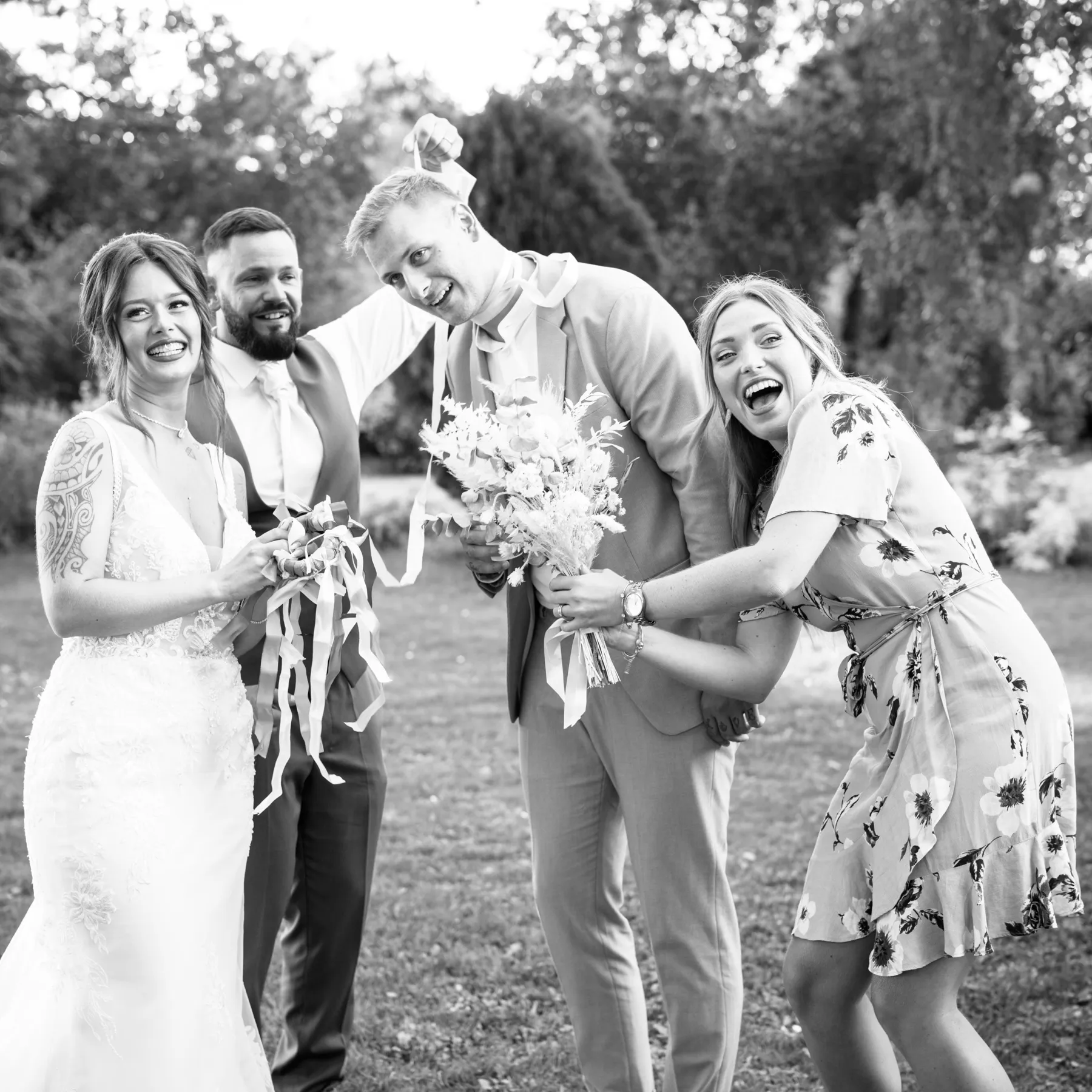 En noir et blanc, les mariés rient avec un couple qui tient le bouquet