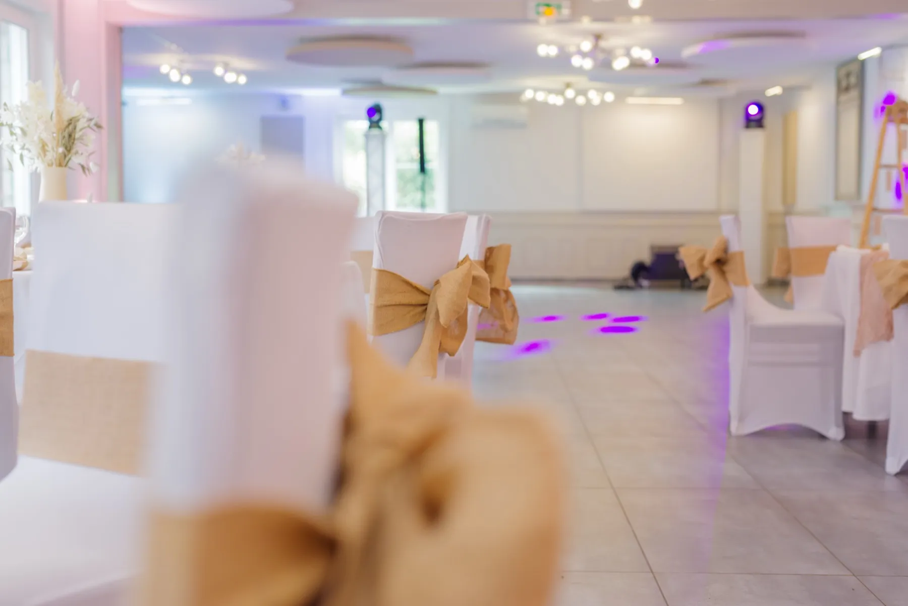 Chaises houssées de blanc et nouées de toile de jute, autour de la piste de danse