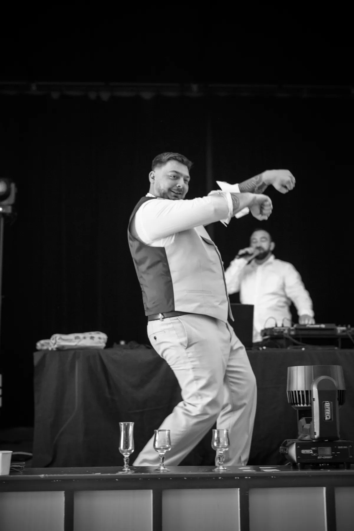 En noir et blanc, le marié danse sur la scène à côté du disc-jockey