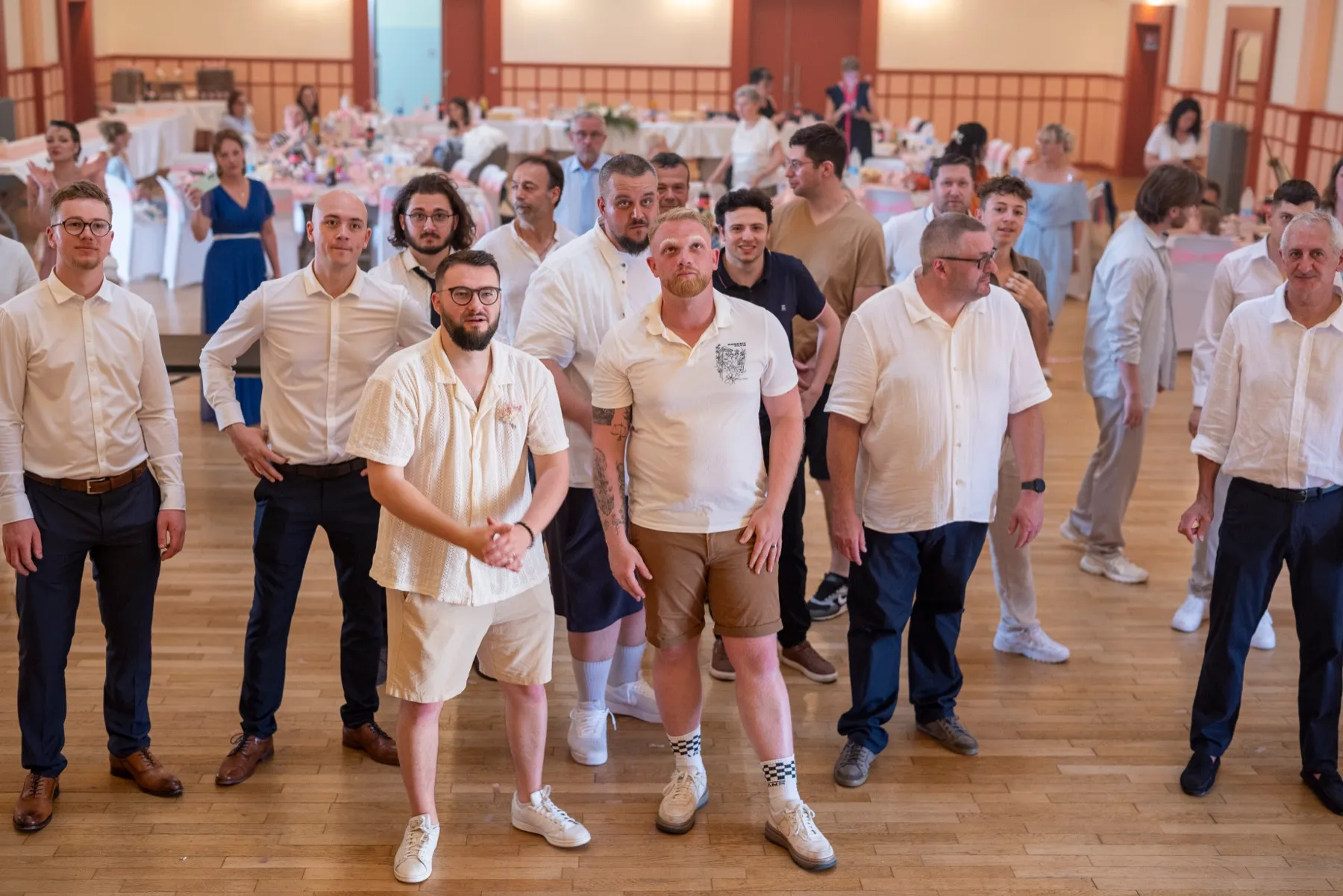 Les hommes de la noce attendent au milieu de la salle des fêtes