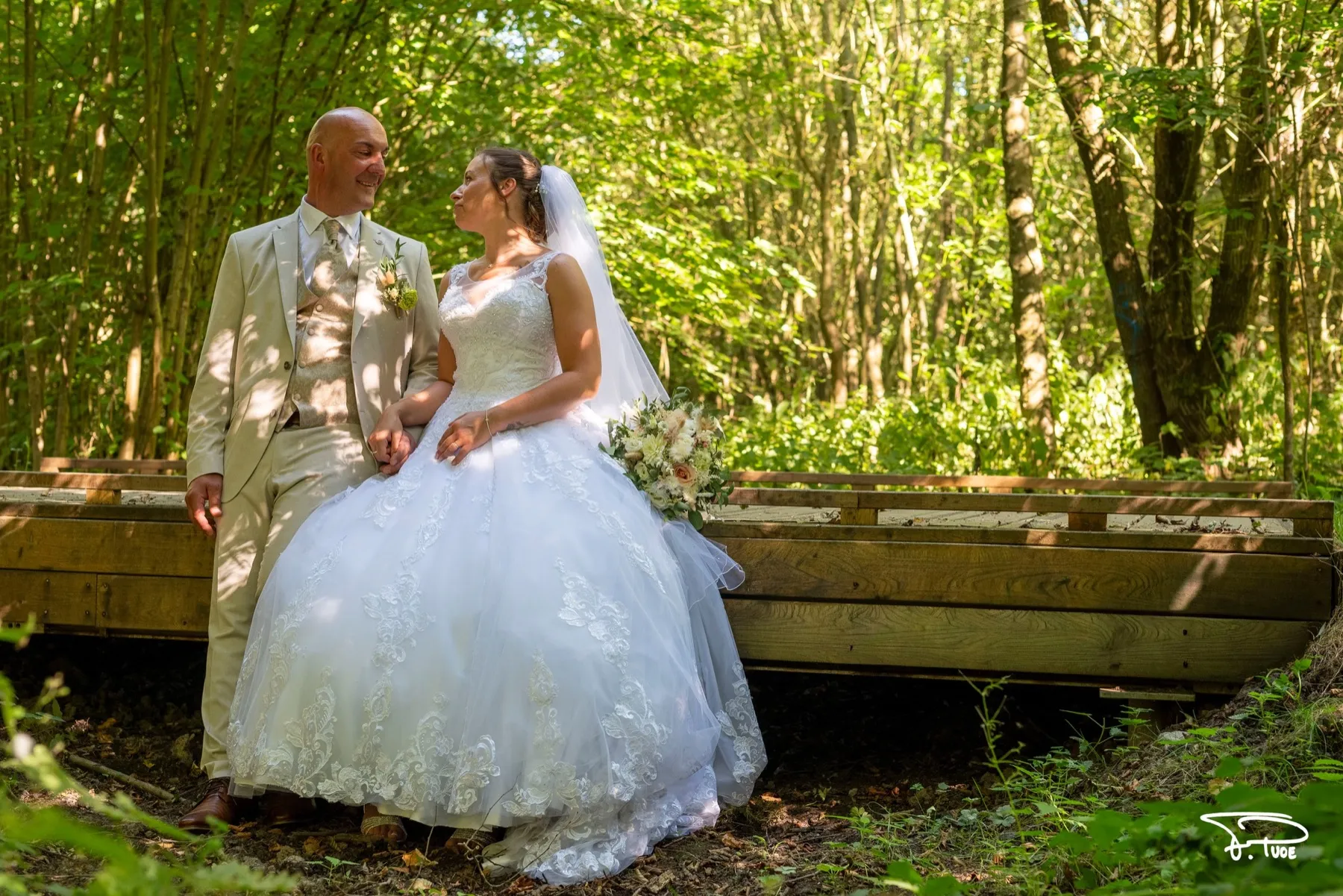 Les mariés assis sur une passerelle en bois au milieu de la forêt