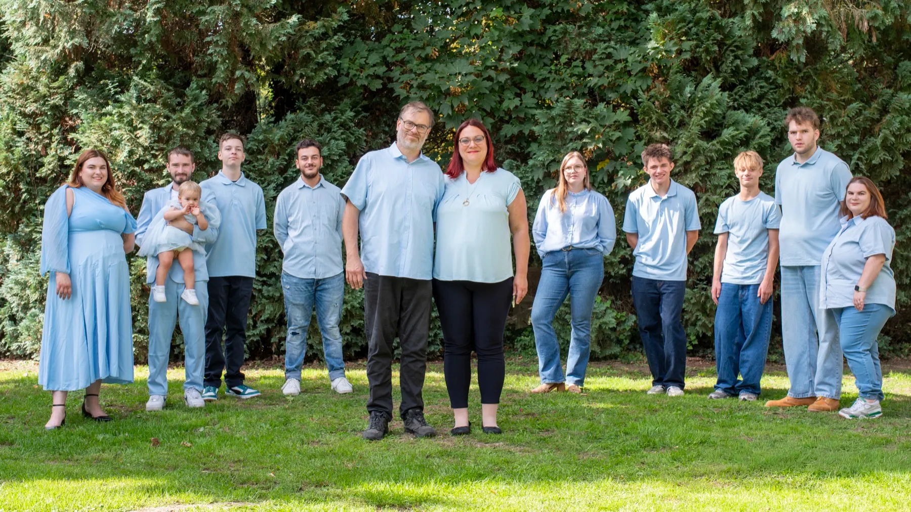 Toute la famille réunie en tenues bleues devant les arbres d’un jardin